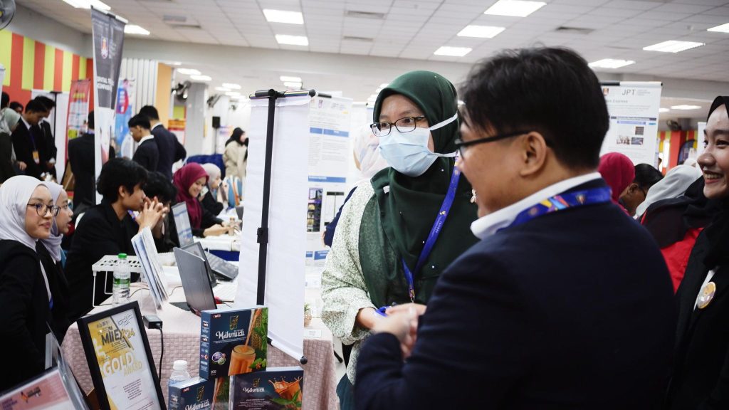i-SIIDEC 2024: A visitor talking with a team member at the booth