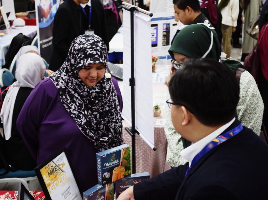i-SIIDEC 2024: A visitor talking with a team member at the booth