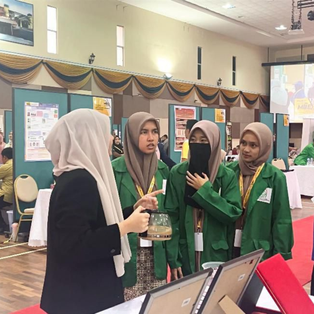 MIIEX’24: A team member explaining a drink to students in green jackets