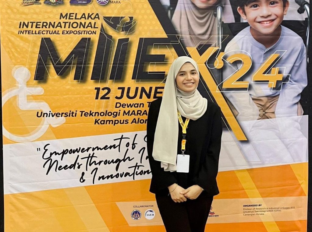MIIEX’24: A team member in front of the MIIEX’24 banner